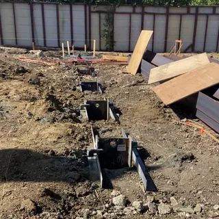 Steel piles set in drilled holes across a graded lot